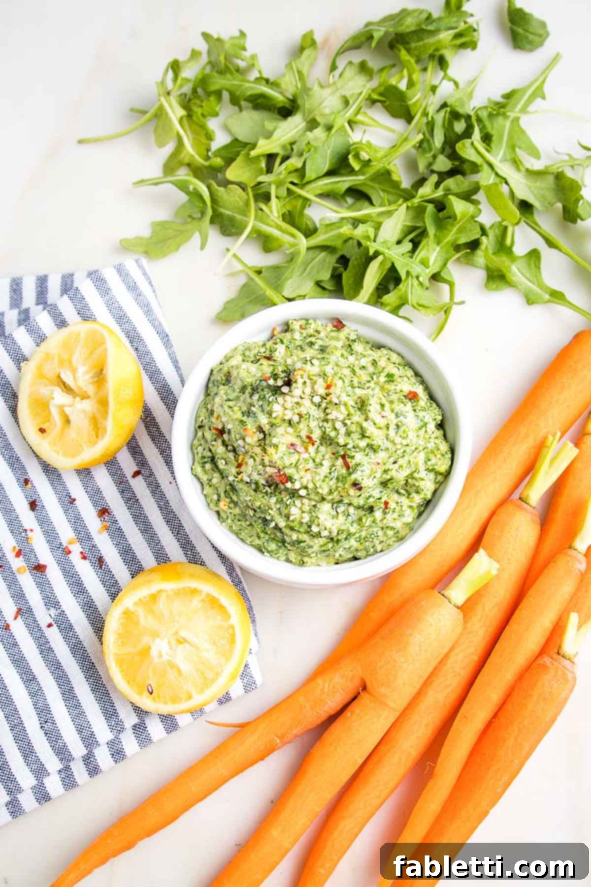 Vibrant Carrot Top Pesto 2 Carrots, carrot greens and lemons surround a bowl of carrot top pesto.