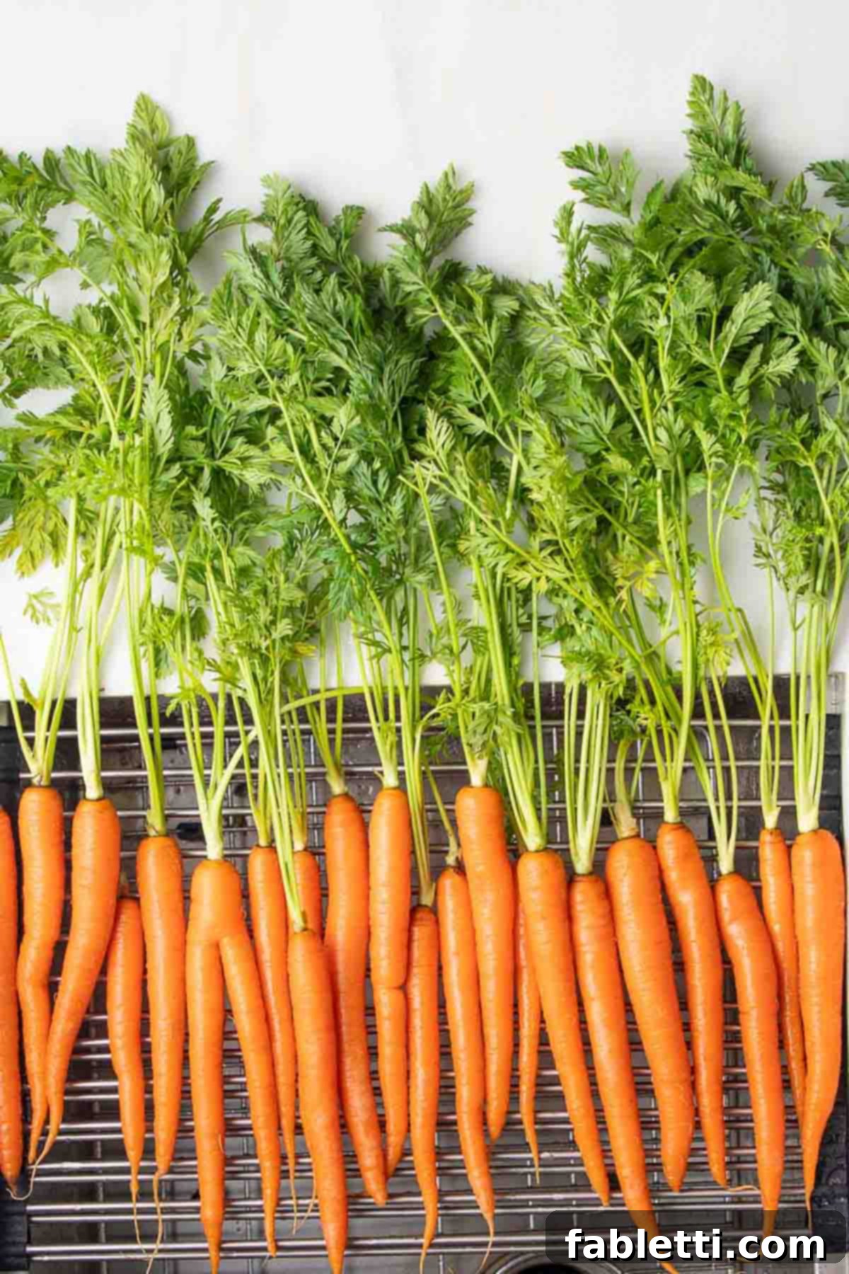 Vibrant Carrot Top Pesto 3 Fresh carrots with their greens attached on a wire rack.