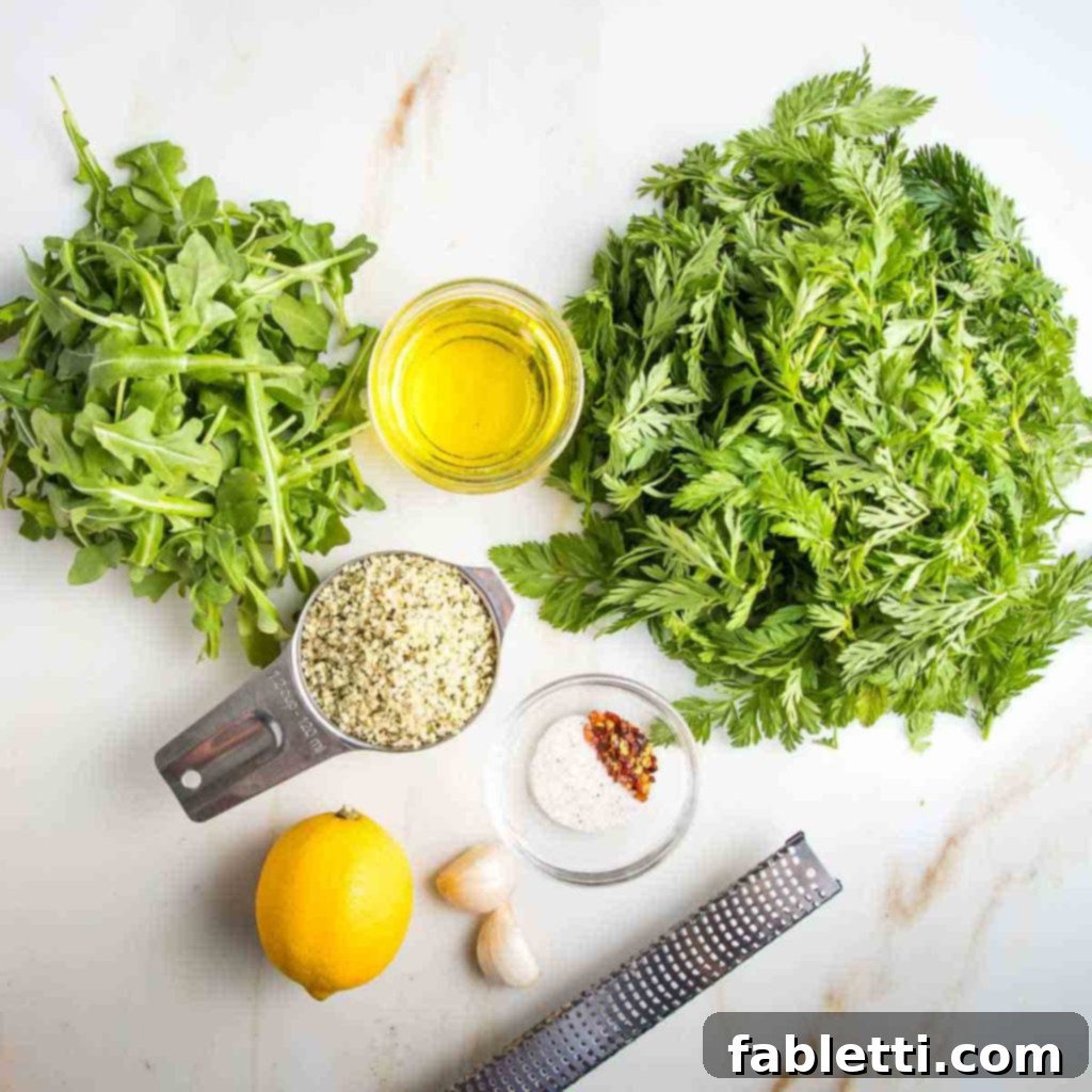 Vibrant Carrot Top Pesto 4 Pile of carrot greens and pile of arugula, plus hemp seeds, olive oil, lemon, garlic and spices.