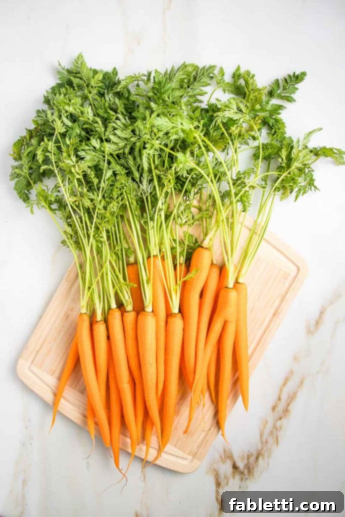 Vibrant Carrot Top Pesto 5 Bunch of carrots on a cutting board with their greens still attached.