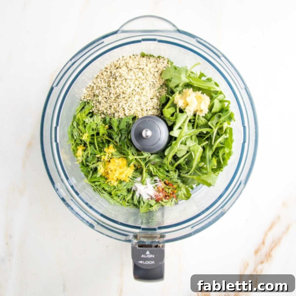 Vibrant Carrot Top Pesto 7 Food processor bowl filled with ingredients for carrot greens pesto.