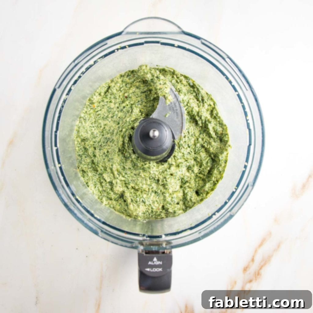 Vibrant Carrot Top Pesto 9 Creamy green pesto in the bowl of a food processor.