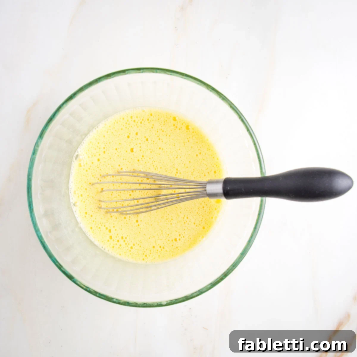 Frothy whisked eggs in a glass bowl.