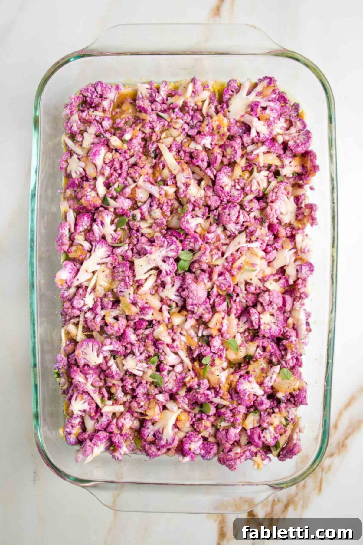 Purple cauliflower in an egg casserole, sprinkled with fresh oregano leaves.