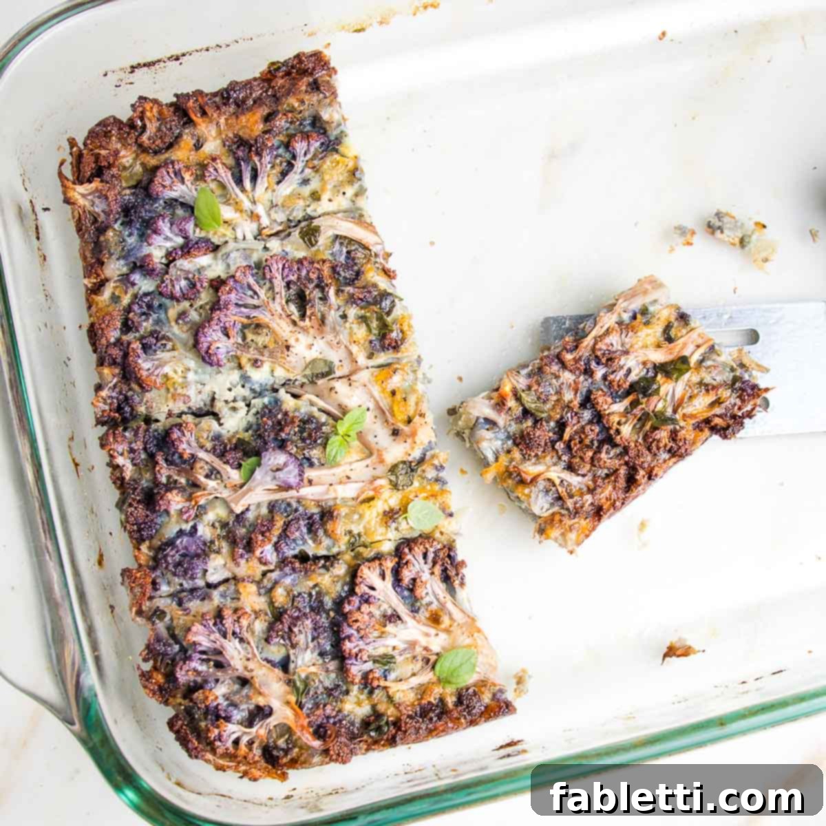 9 x 13 pyrex with a last row of pieces of kugel and one piece onto a small spatula, showcasing the crispy edges.