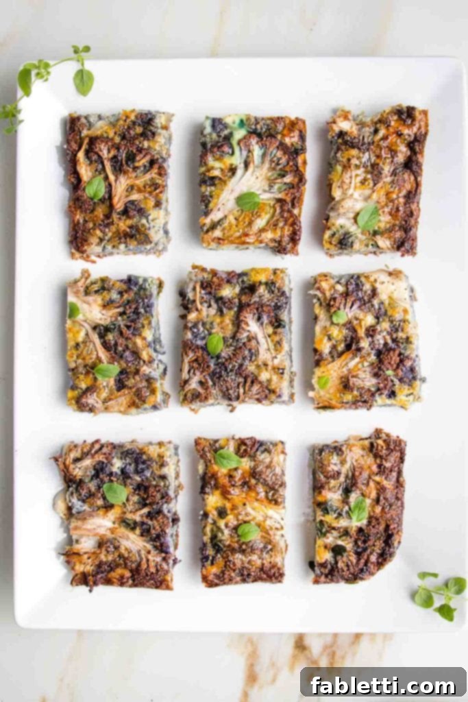 Rectangular White plate, filled with pieces of cauliflower kugel that have been sprinkled with fresh oregano.