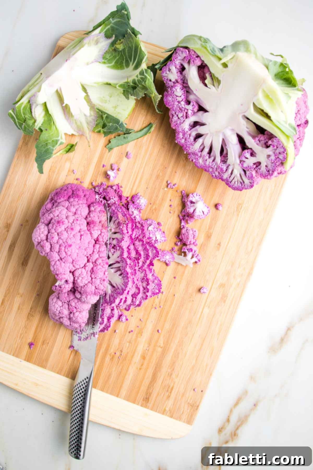 Head of purple cauliflower cut in half and then one half cut into long thin slices.