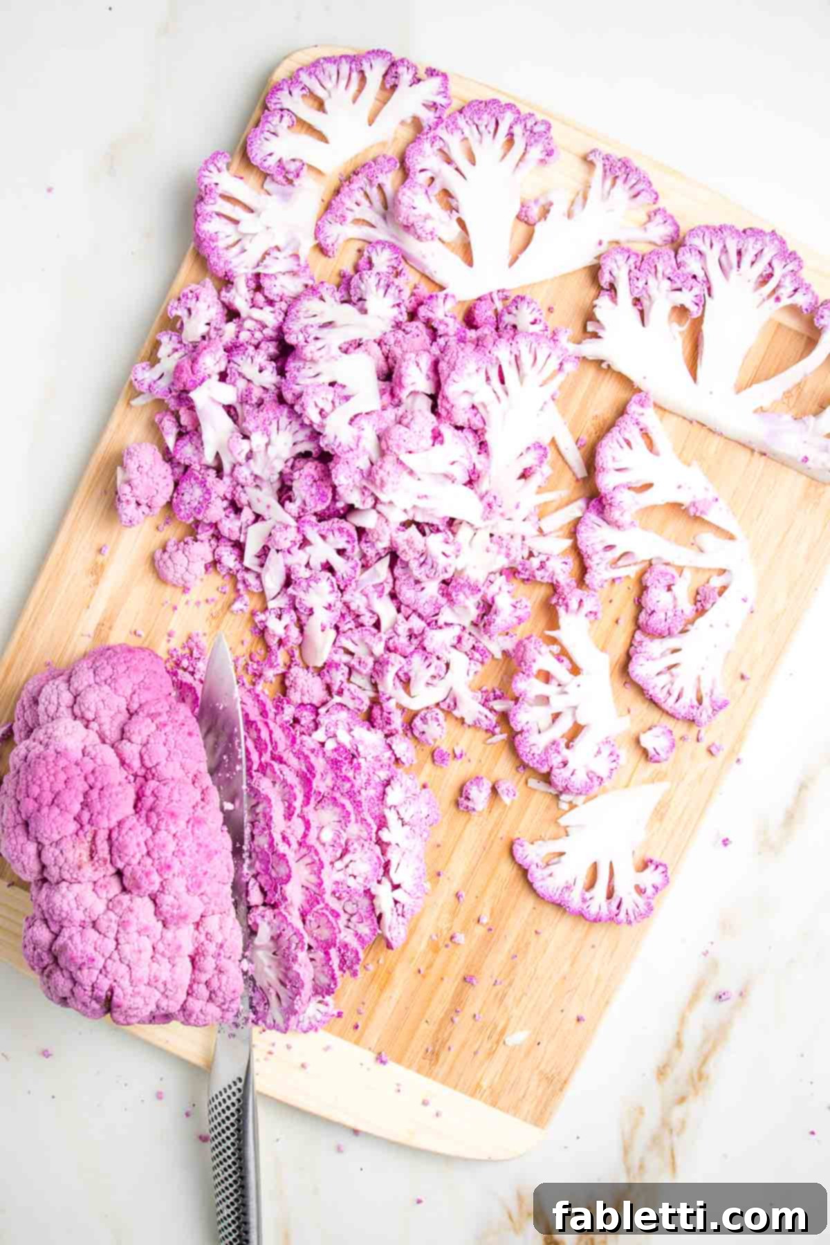 Thinly slicing a head of purple cauliflower.