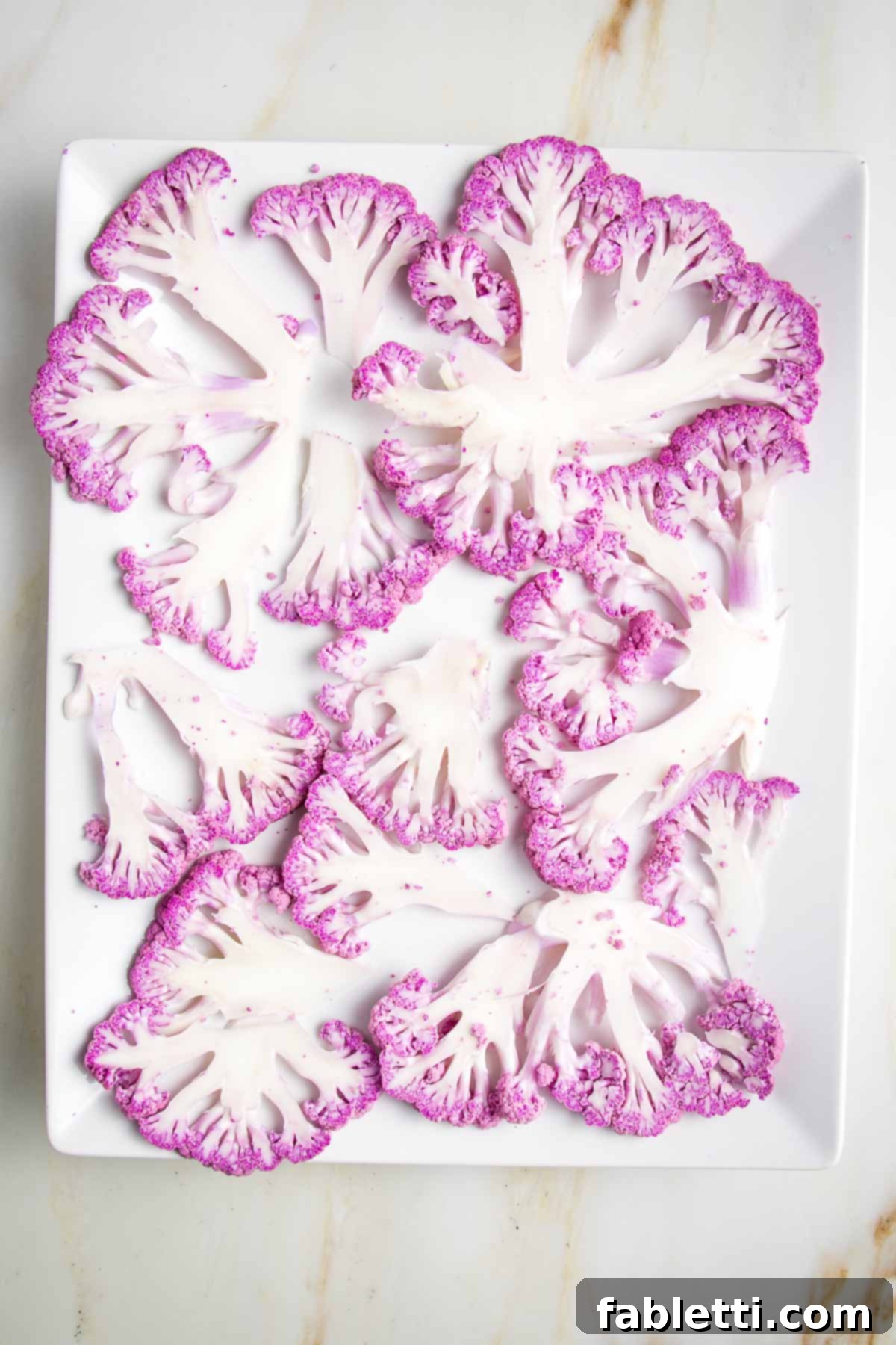 Super thin slices of purple cauliflower, artfully arranged on a platter.