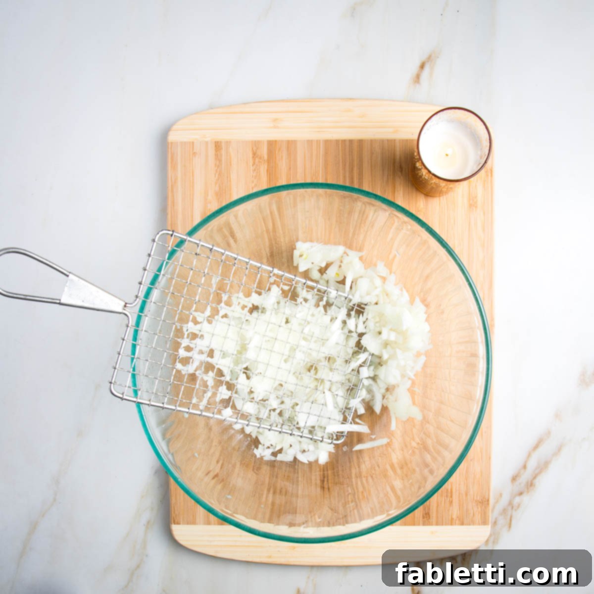 Shredding a yellow onion with a potato shredder.