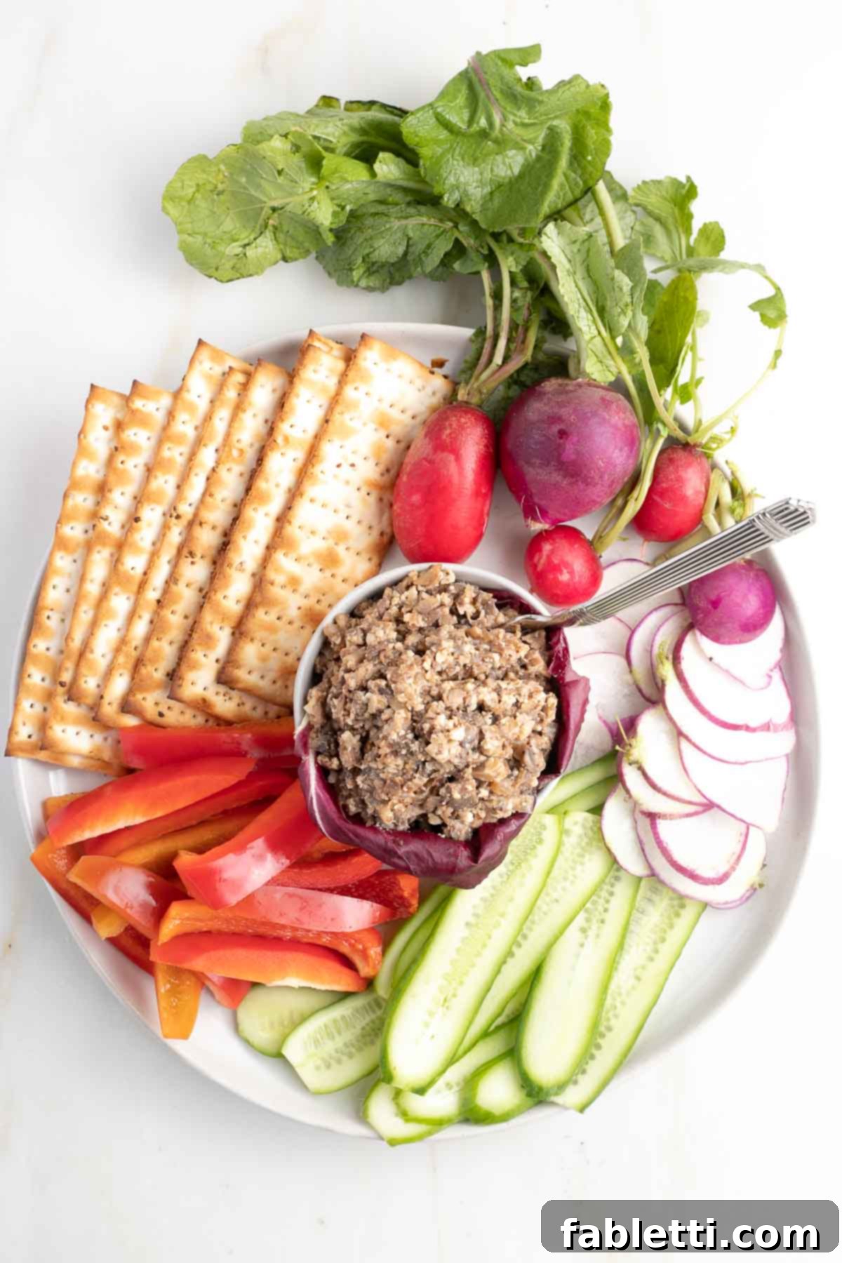 Vegetarian Chopped Liver in a small dish surrounded by raw vegetables and matzo crackers.