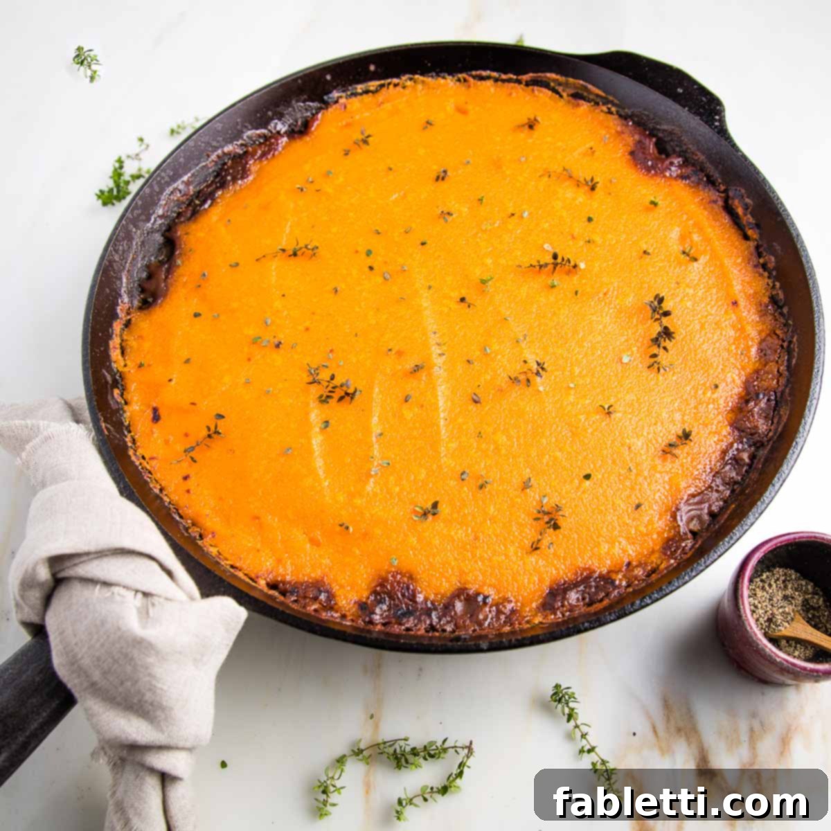 Sun-Kissed Vegan Shepherd's Pie 18 Cast iron skillet filled with vegan shepherd's pie that's topped with sweet potato mash and sprinkled with fresh thyme.