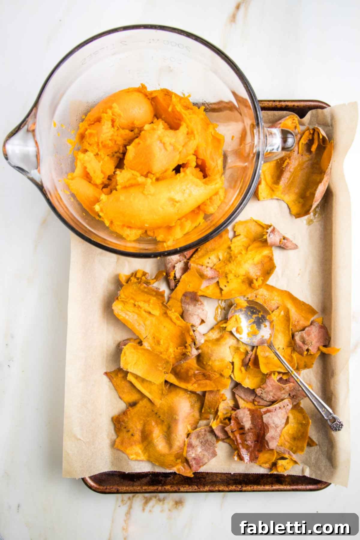 Sun-Kissed Vegan Shepherd's Pie 8 Scooping out the bright orange flesh from the skins of baked sweet potatoes.