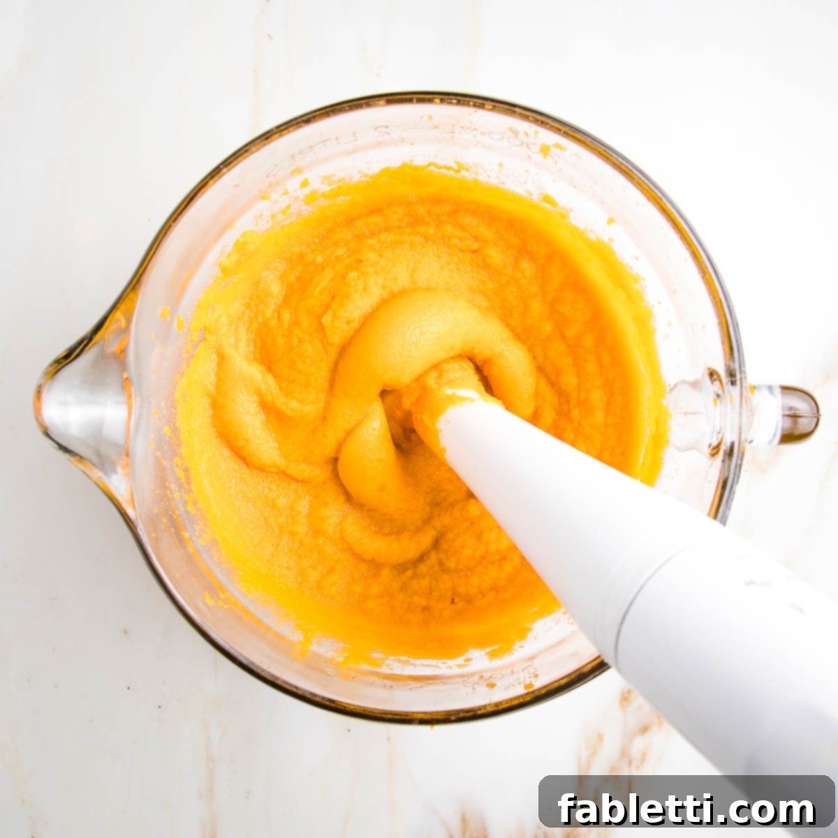 Sun-Kissed Vegan Shepherd's Pie 10 Immersion blender pureeing the bright orange flesh of cooked sweet potatoes.