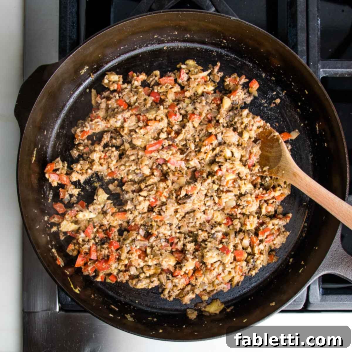 Satisfying Plant-Powered Zucchini Boats 11 The skillet now shows the fully combined plant-based filling, a rich and savory mixture of vegetables, walnuts, and tamari, after being thoroughly stirred with the heat turned off.