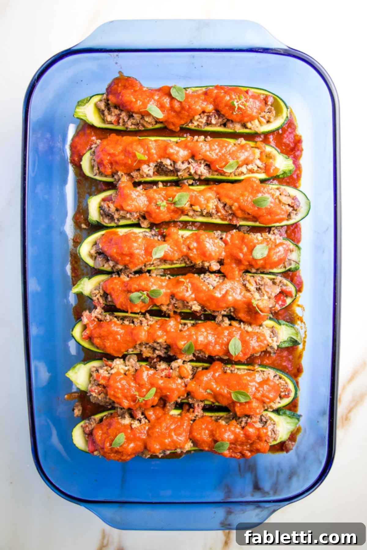 Satisfying Plant-Powered Zucchini Boats 13 The zucchini boats are now fully stuffed with the savory plant-based filling, generously topped with marinara sauce, and freshly garnished with vibrant herbs, ready for their final bake.