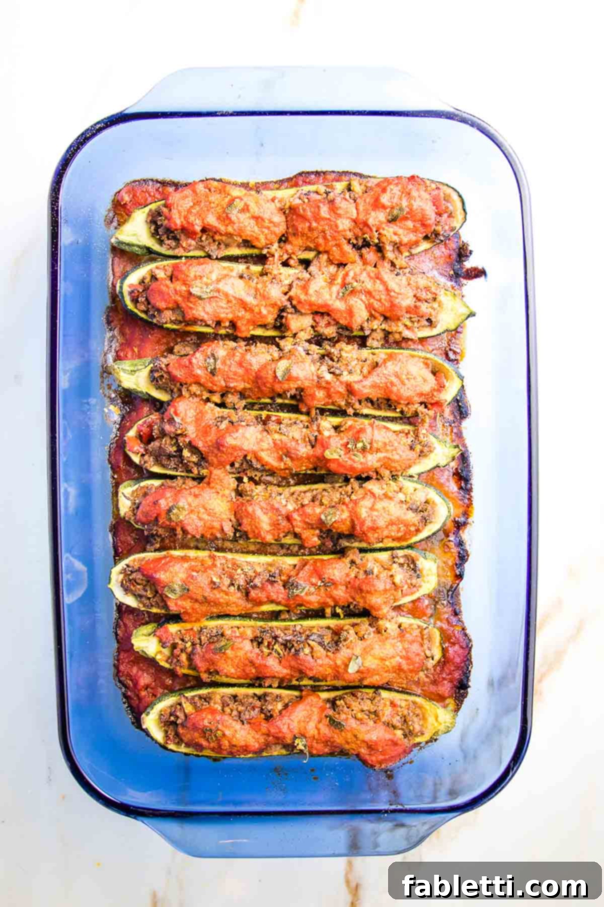 Satisfying Plant-Powered Zucchini Boats 15 Beautifully baked stuffed zucchini boats, bubbling hot and golden on top, nestled in a casserole dish, ready to be served. The filling is tender and meaty, promising a delightful culinary experience.