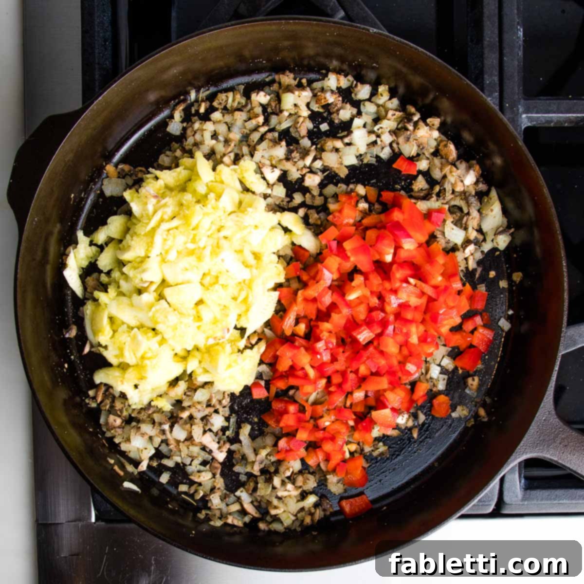Satisfying Plant-Powered Zucchini Boats 9 The cast iron skillet now holds the aromatic mixture, enriched with diced bell peppers and the roughly chopped zucchini pulp that was previously set aside. The ingredients are being stirred as they cook, releasing their juices and tenderizing, yet maintaining a desirable firm texture.