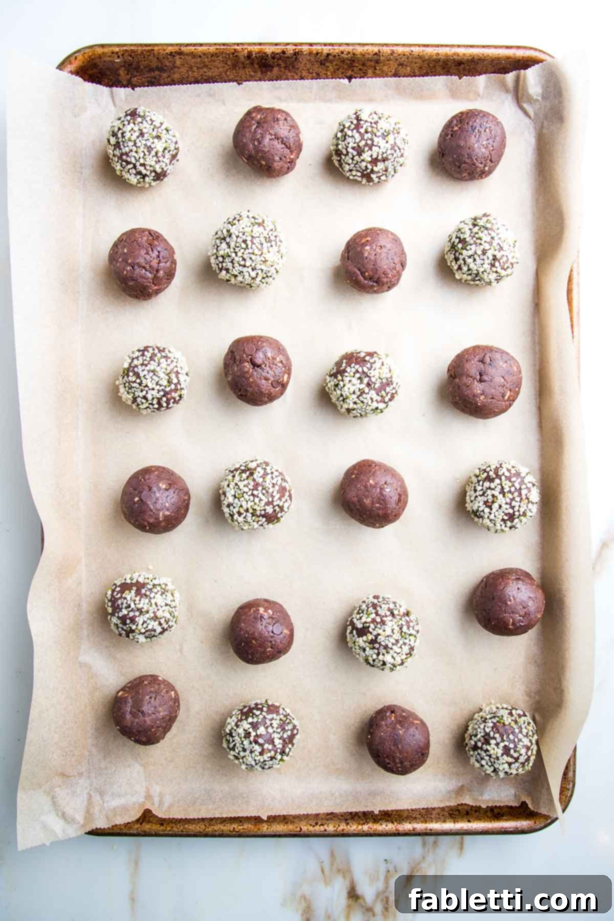 Irresistible Cookie Dough Poppers 15 Tray lined with unbleached parchment paper and filled with chocolate balls...some of them are rolled into hemp seeds.