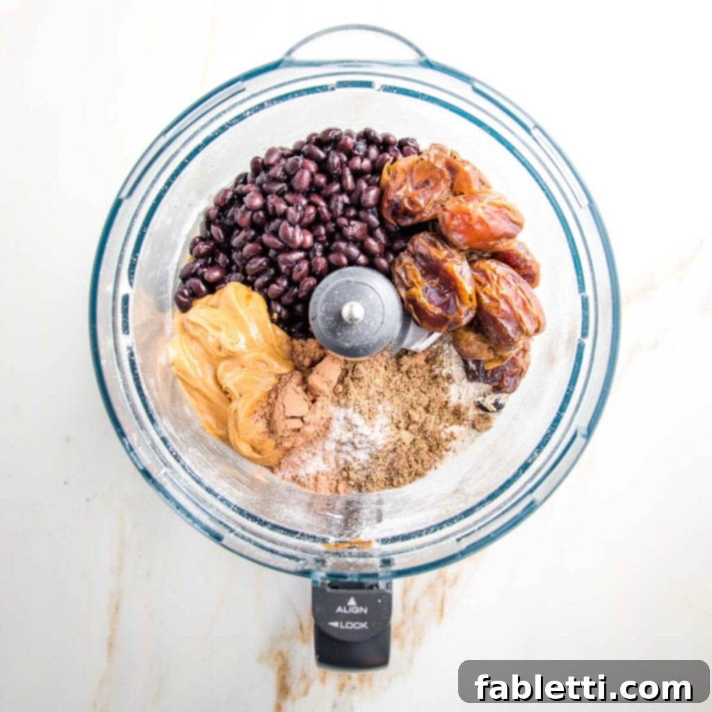 Irresistible Cookie Dough Poppers 6 Food processor bowl filled with black beans, peanut butter, cacao powder, dates, ground flax and salt