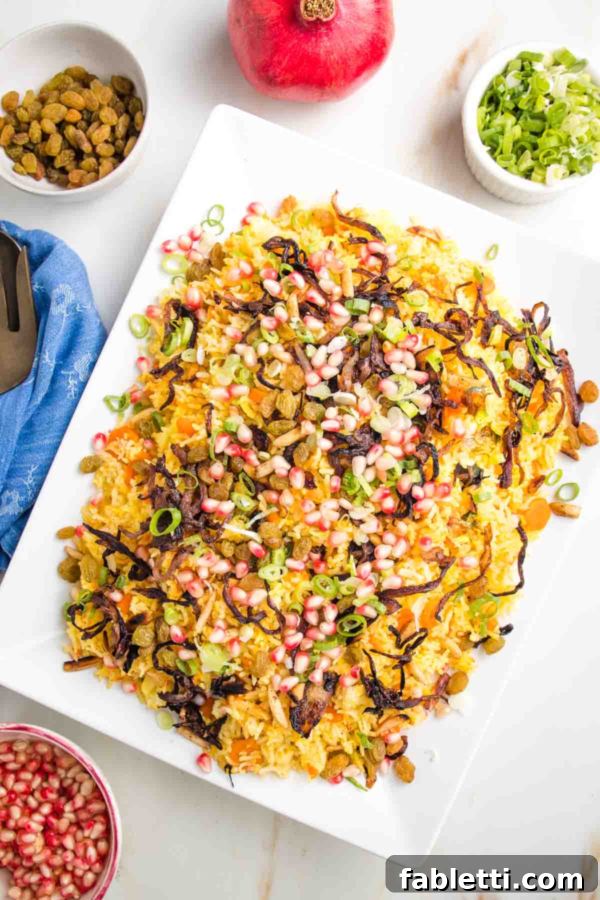 Platter of jeweled rice with colorful pomegranate, pistachio, caramelized onions and scallions.