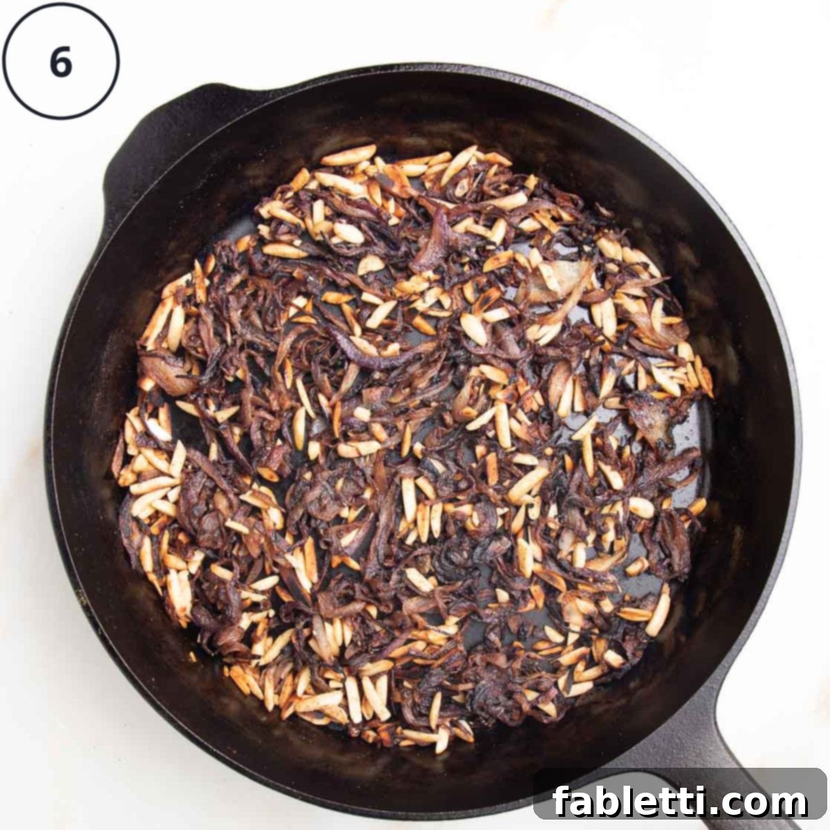 Caramelized onions, seasoning and nuts in a cast iron skillet, numbered "6".