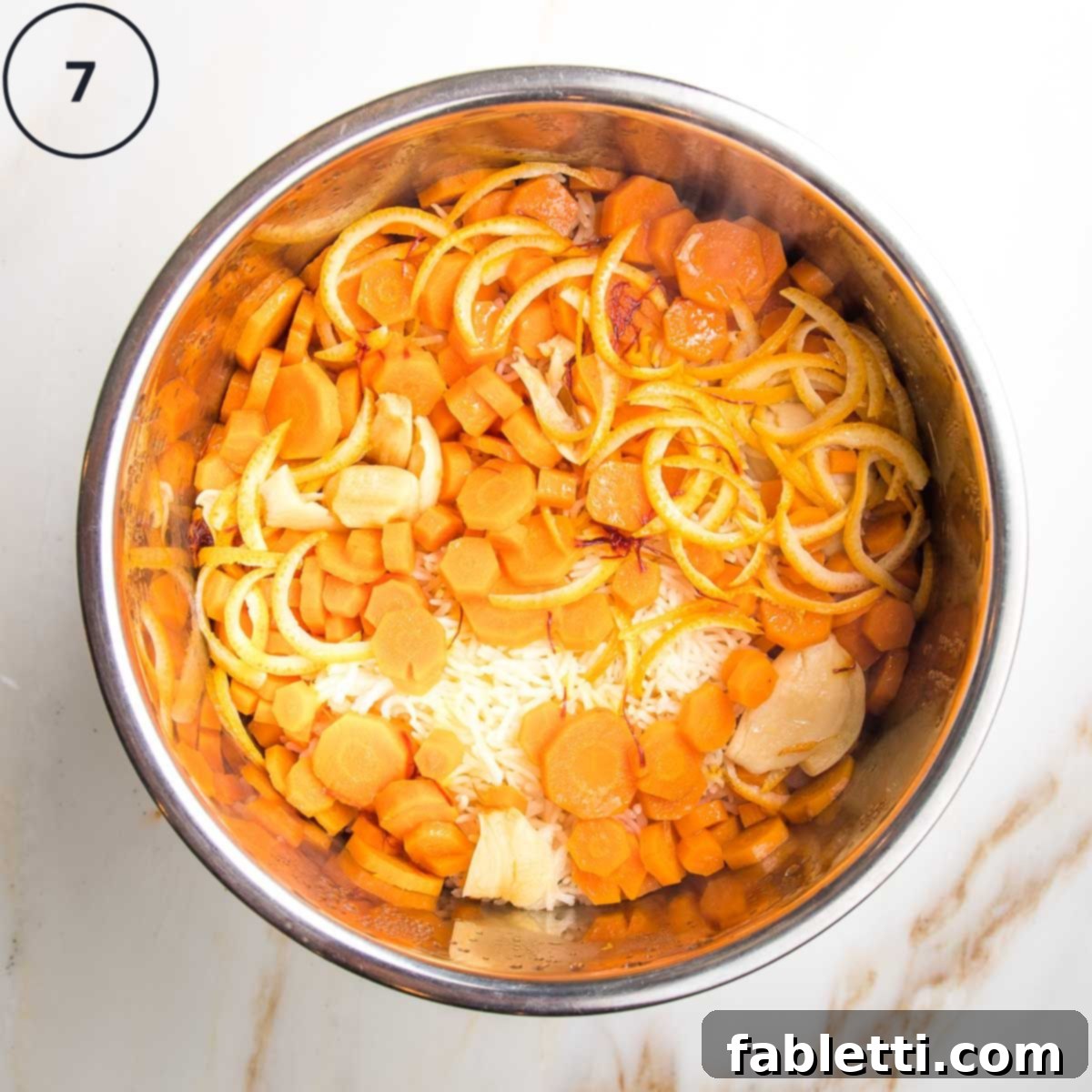 Instant pot insert with cooked rice, veggies, spices and orange peels.