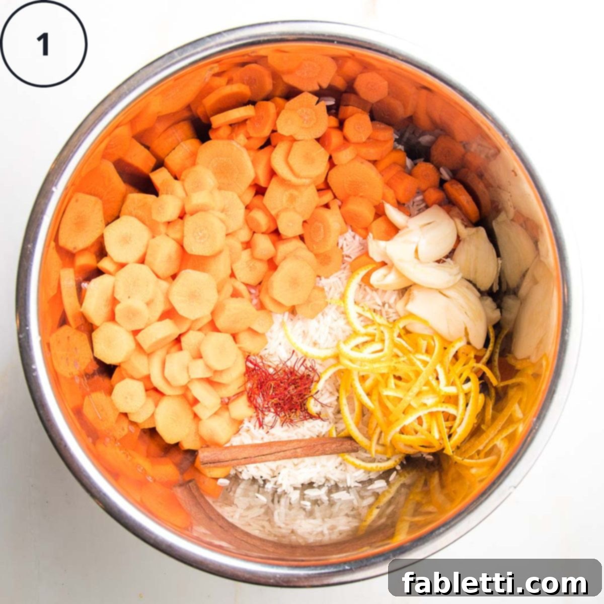 Instant Pot insert with rice, carrot rounds, spices, garlic, cinnamon stick and orange peels.