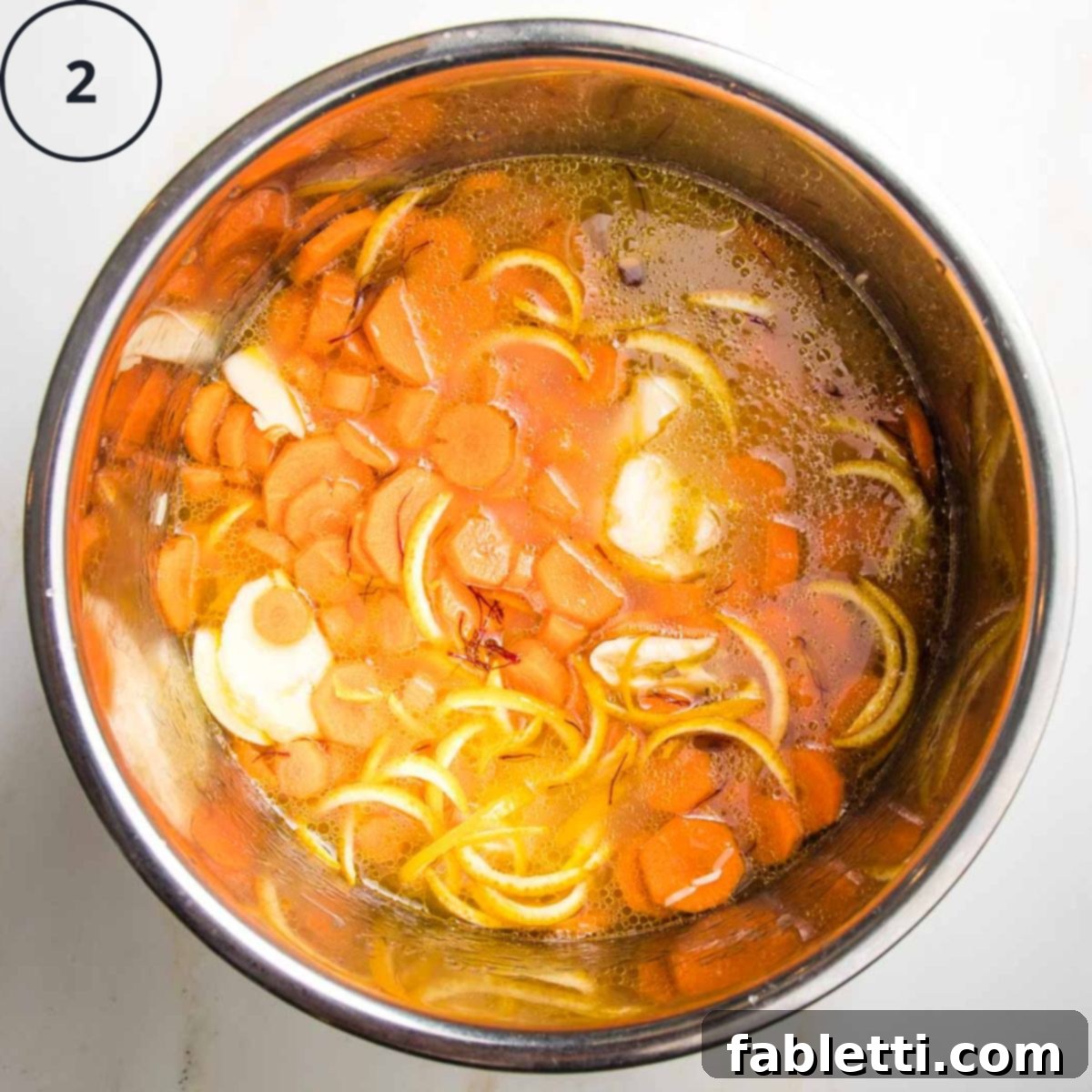 Instant pot with rice, carrot rounds, orange peels and spices, covered with water.
