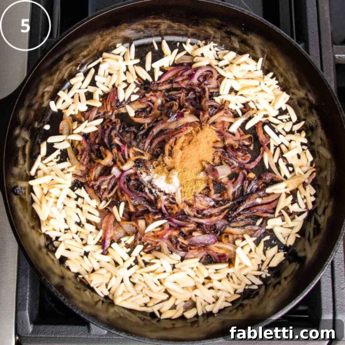 Caramelized onions in a cast iron skillet with slivered almonds sprinkled into the pan.