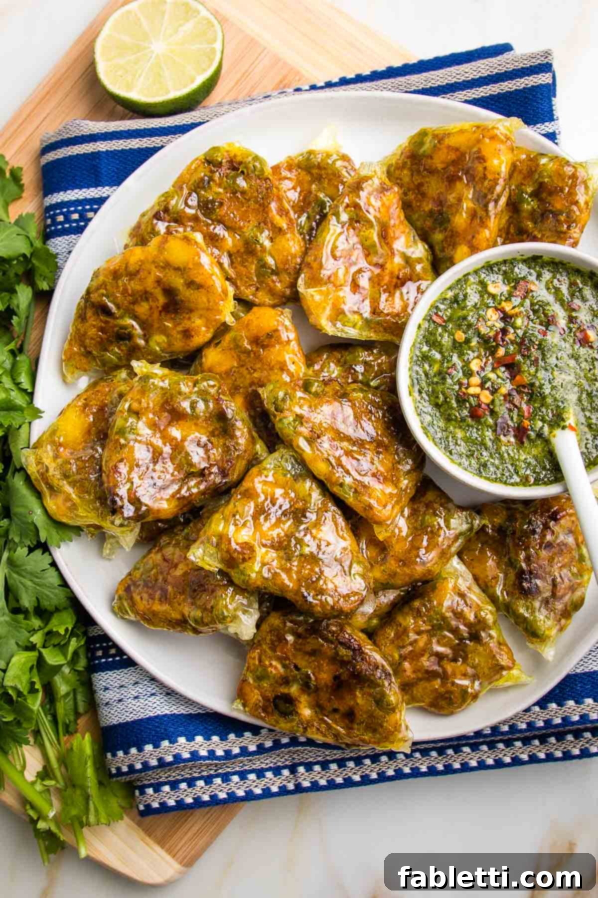 Crispy Baked Samosas with Zesty Cilantro Chutney 2 Plate of baked samosas with a small dish of green chutney.