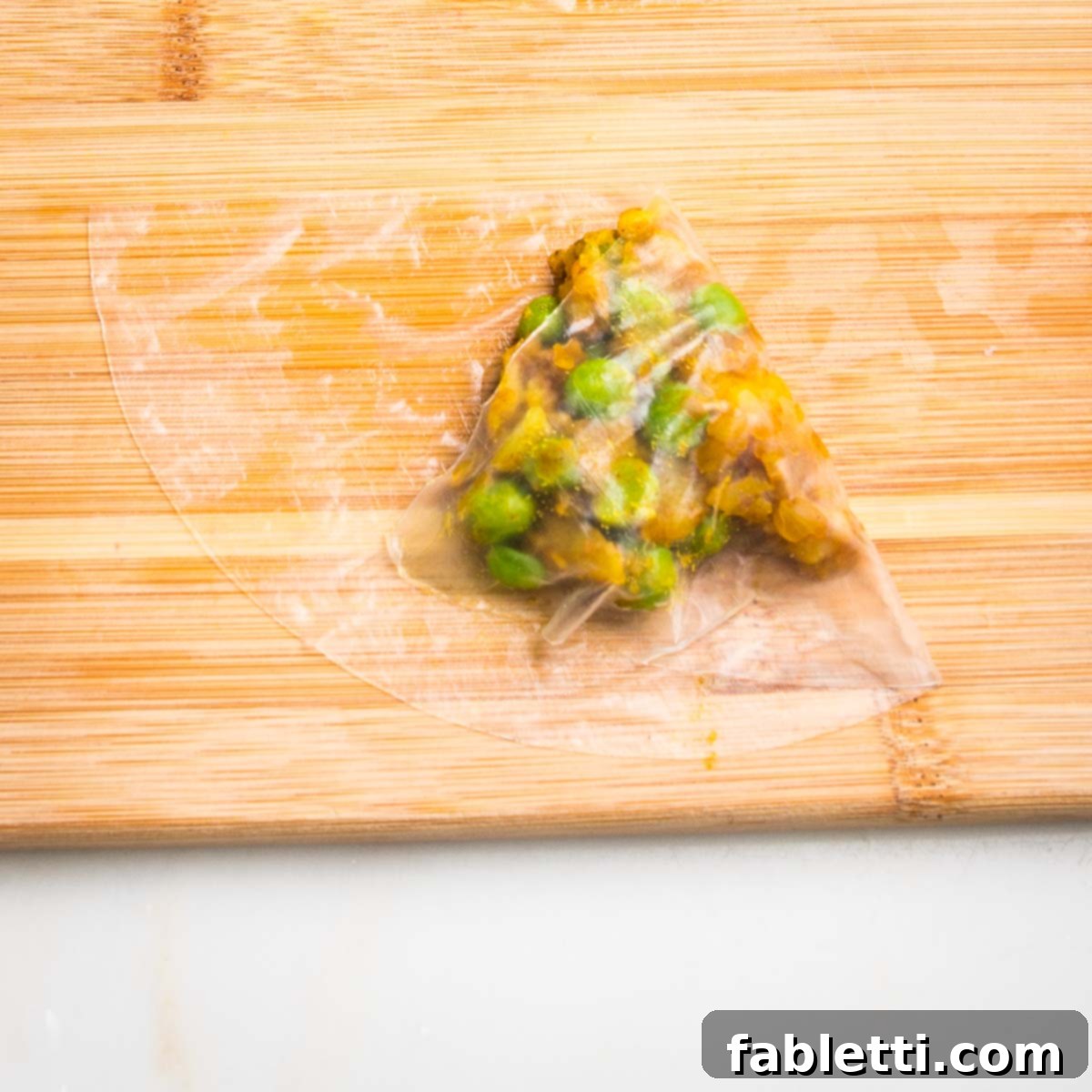 Crispy Baked Samosas with Zesty Cilantro Chutney 12 Half moon of wet rice paper, with a scoop of potato samosa filling, with one side folded over.