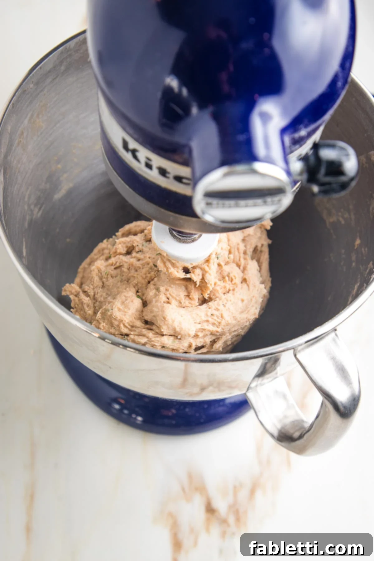 Fluffy Vegan Dinner Rolls 11 Stand mixer with batch of dough that has pulled away from the sides of the bowl, yet stuck onto the paddle attachment.