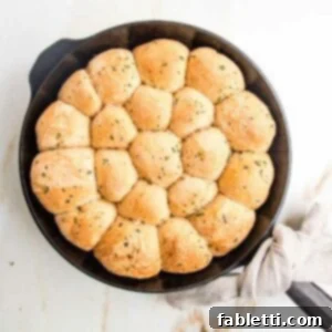 Fluffy Vegan Dinner Rolls 21 Cast iron skillet filled with round herby dinner rolls.