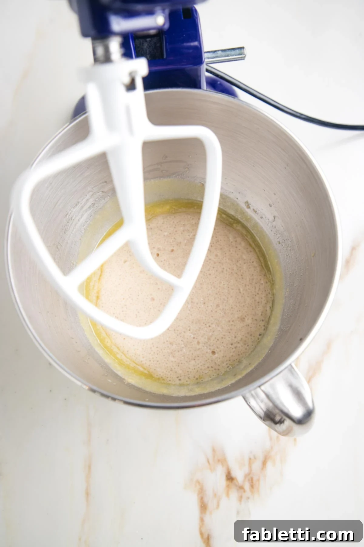 Fluffy Vegan Dinner Rolls 8 proofed yeast mixture in the bowl of a stand mixer with the paddle attachment.