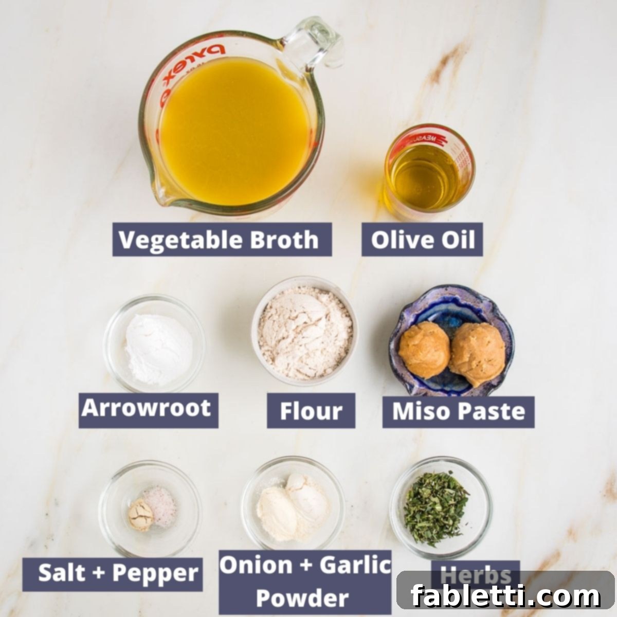 Whip Up Perfect Vegan Gravy 4 A visually organized flat lay of all the easy vegan gravy ingredients, clearly labeled: vegetable broth, olive oil, arrowroot powder, miso paste, gluten-free flour, a bundle of fresh herbs, onion powder, and garlic powder. This setup emphasizes the simplicity and natural origins of each component.
