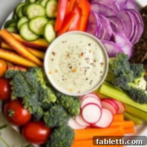 Deliciously Healthy Homemade Ranch 9 Creamy vegan ranch dressing presented in a small bowl, artfully surrounded by a colorful array of fresh, cut-up vegetables, perfect for dipping.