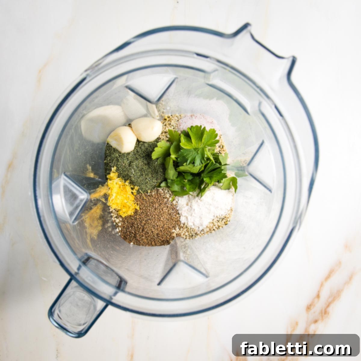 Deliciously Healthy Homemade Ranch 5 All the healthy ranch dressing ingredients are carefully placed inside a high-speed blender, showcasing the vibrant lemon zest, fresh parsley, pungent garlic, aromatic celery seed, fragrant dill, and creamy hemp seeds, ready to be blended into a smooth dressing.