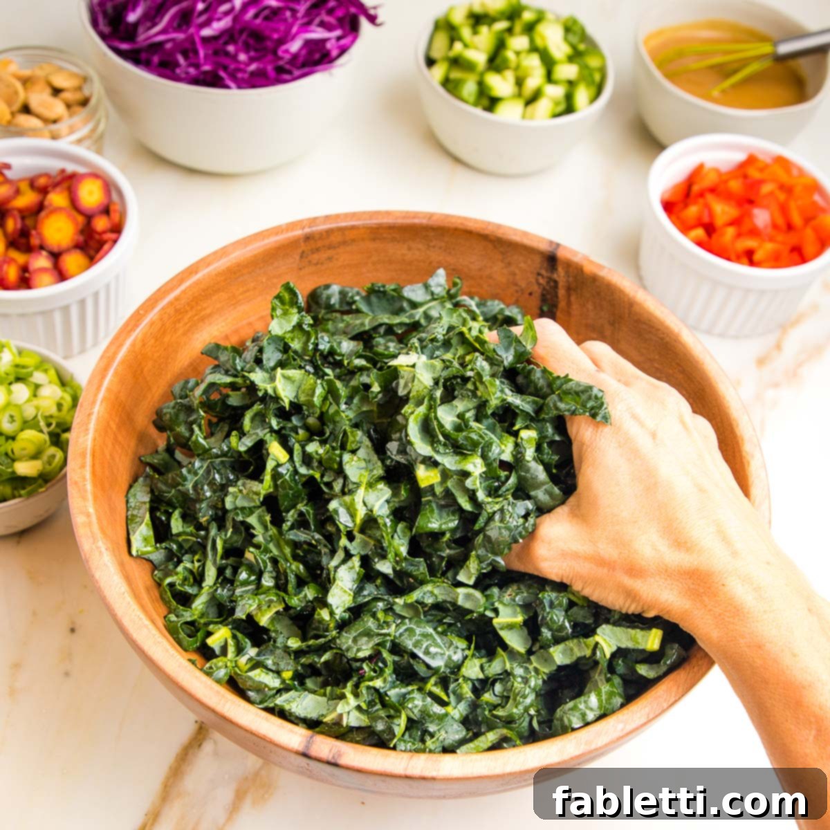 Rustic Tuscan Chopped Kale Medley 7 Wooden bowl, filled with chopped tuscan kale, being massaged by hand.