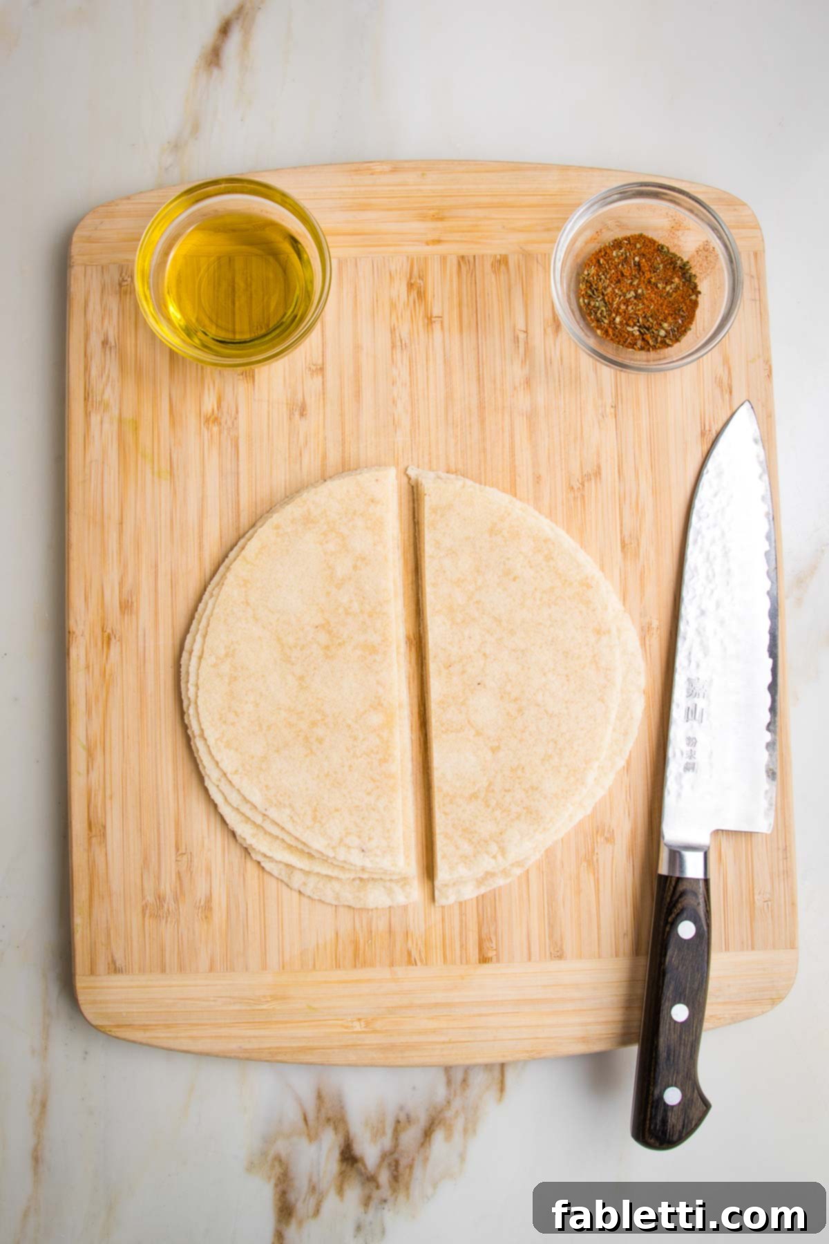 Hearty Vegan Taco Soup with Crispy Tortilla Strips 6 Wooden board with a small dish of olive oil and another small dish with taco seasonings. There are flour tortillas stacked in the center with a sharp knife off to the side, the tortillas have been cut in half.