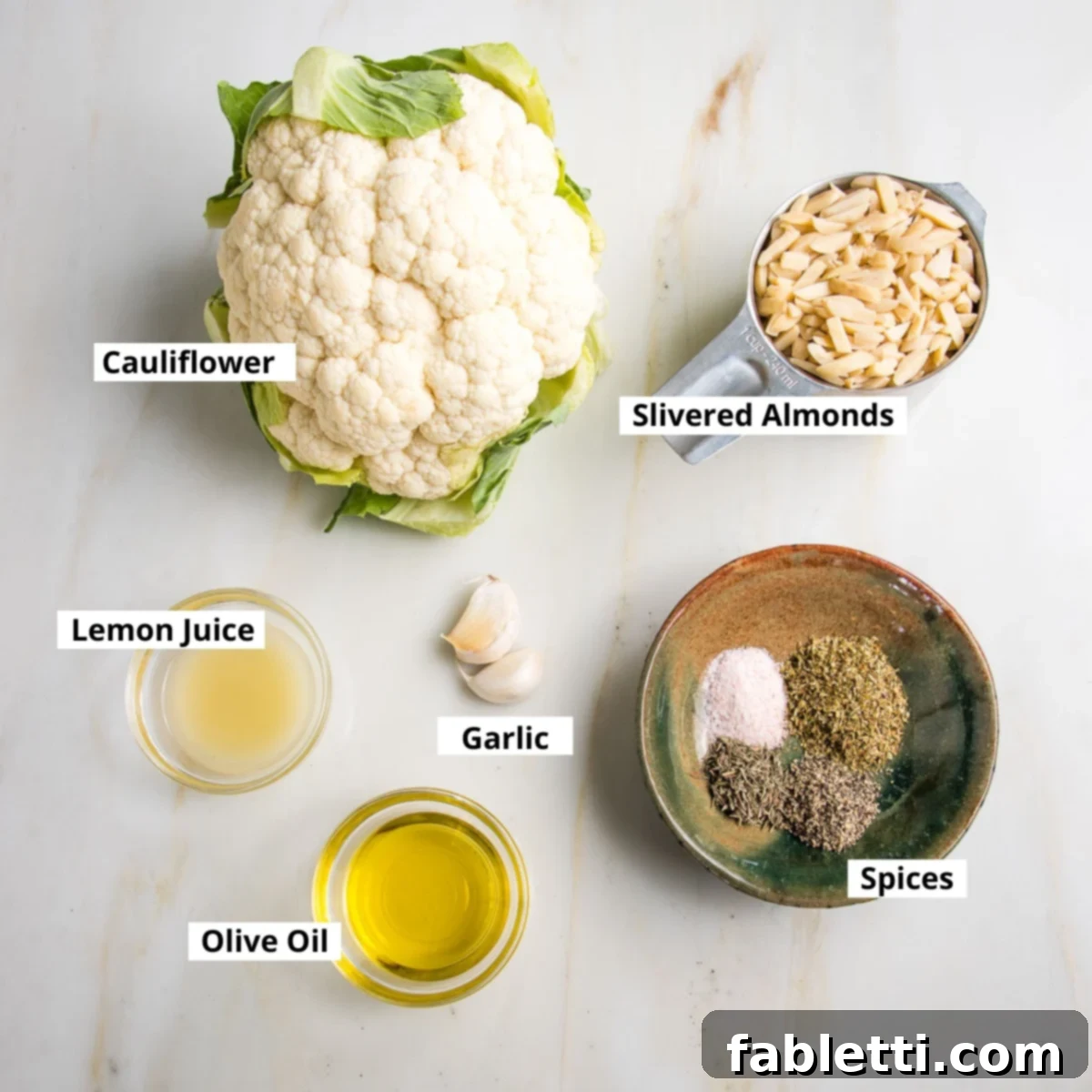 Labeled ingredients for vegan ricotta: cauliflower, slivered almonds, lemon juice, olive oil, garlic cloves, spices.