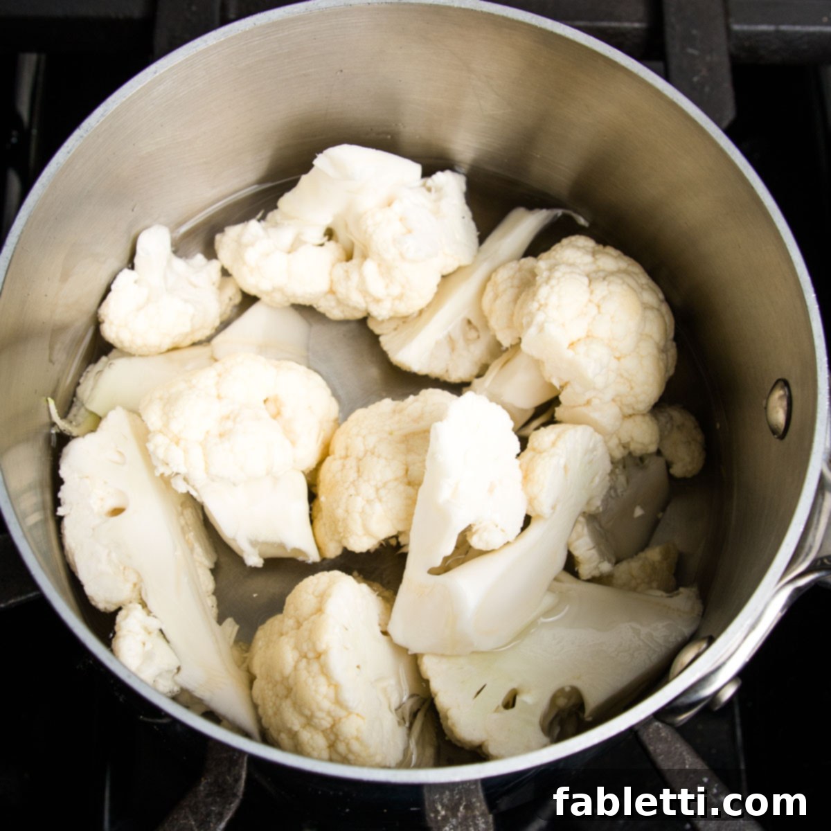 Cauliflower florets in a small pot with an inch of water.