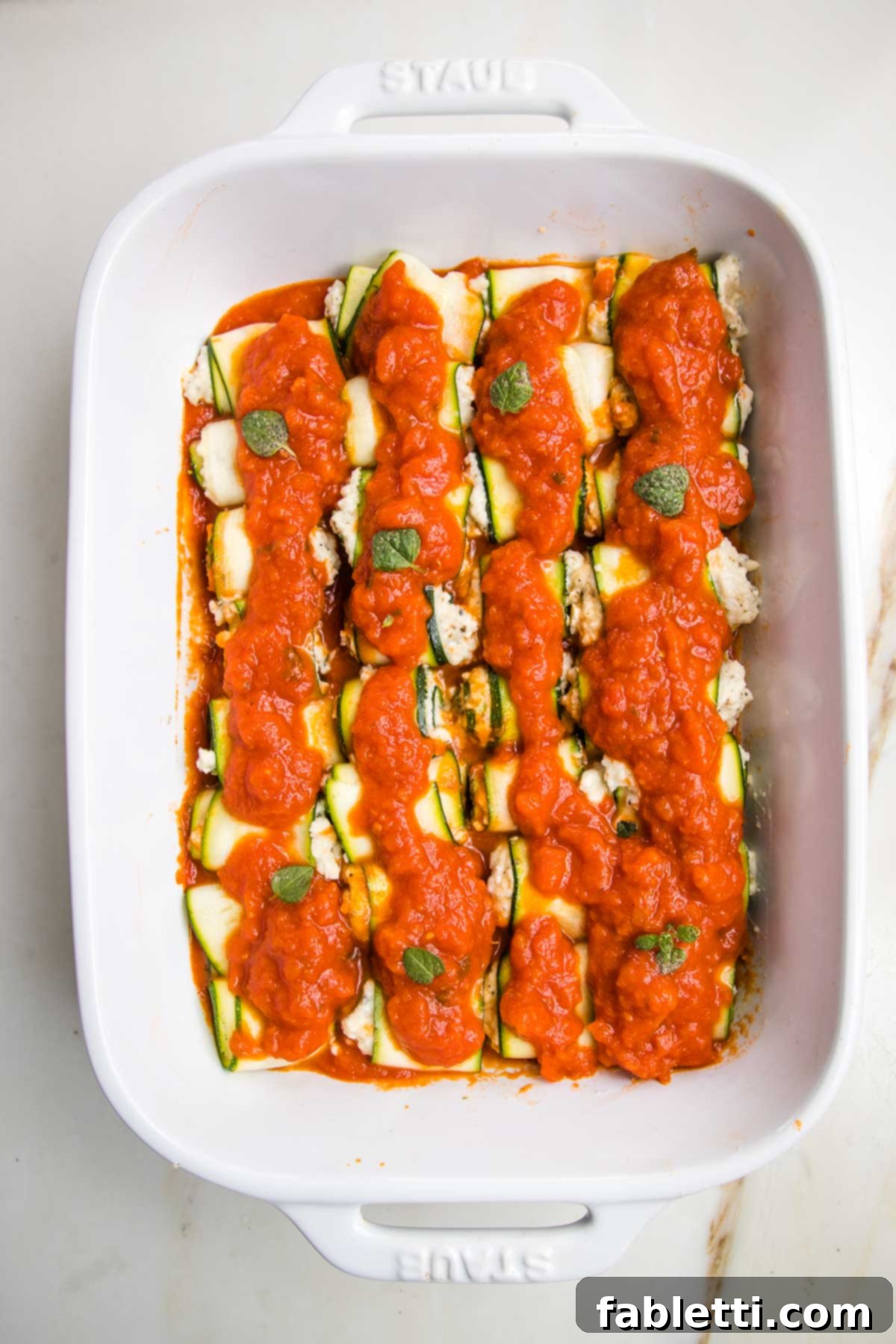 Plant-Based Zucchini Ricotta Rolls 12 White baking pan with marinara, then zucchini ricotta roll ups and another layer of marinara.