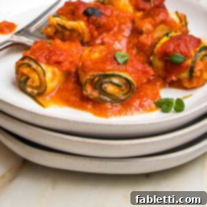 Plant-Based Zucchini Ricotta Rolls 16 Stack of white plates. On top is a plate full of zucchini roll ups filled with vegan ricotta and topped with marinara.