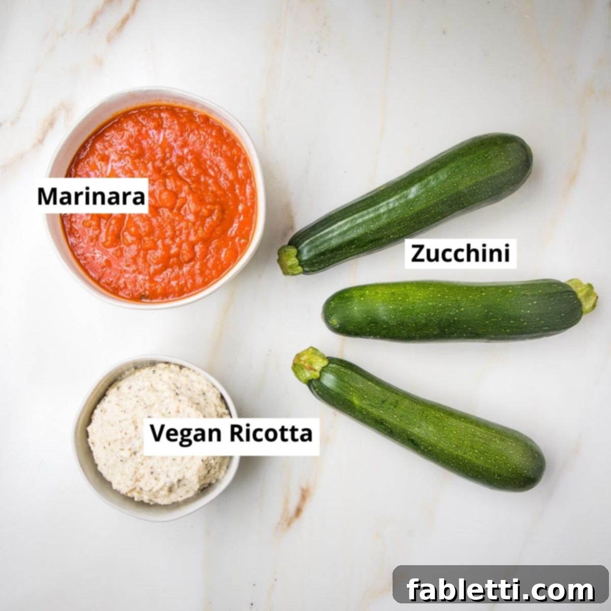 Plant-Based Zucchini Ricotta Rolls 4 Three zucchinis, a bowl of labeled marinara sauce, and a bowl of labeled vegan ricotta.