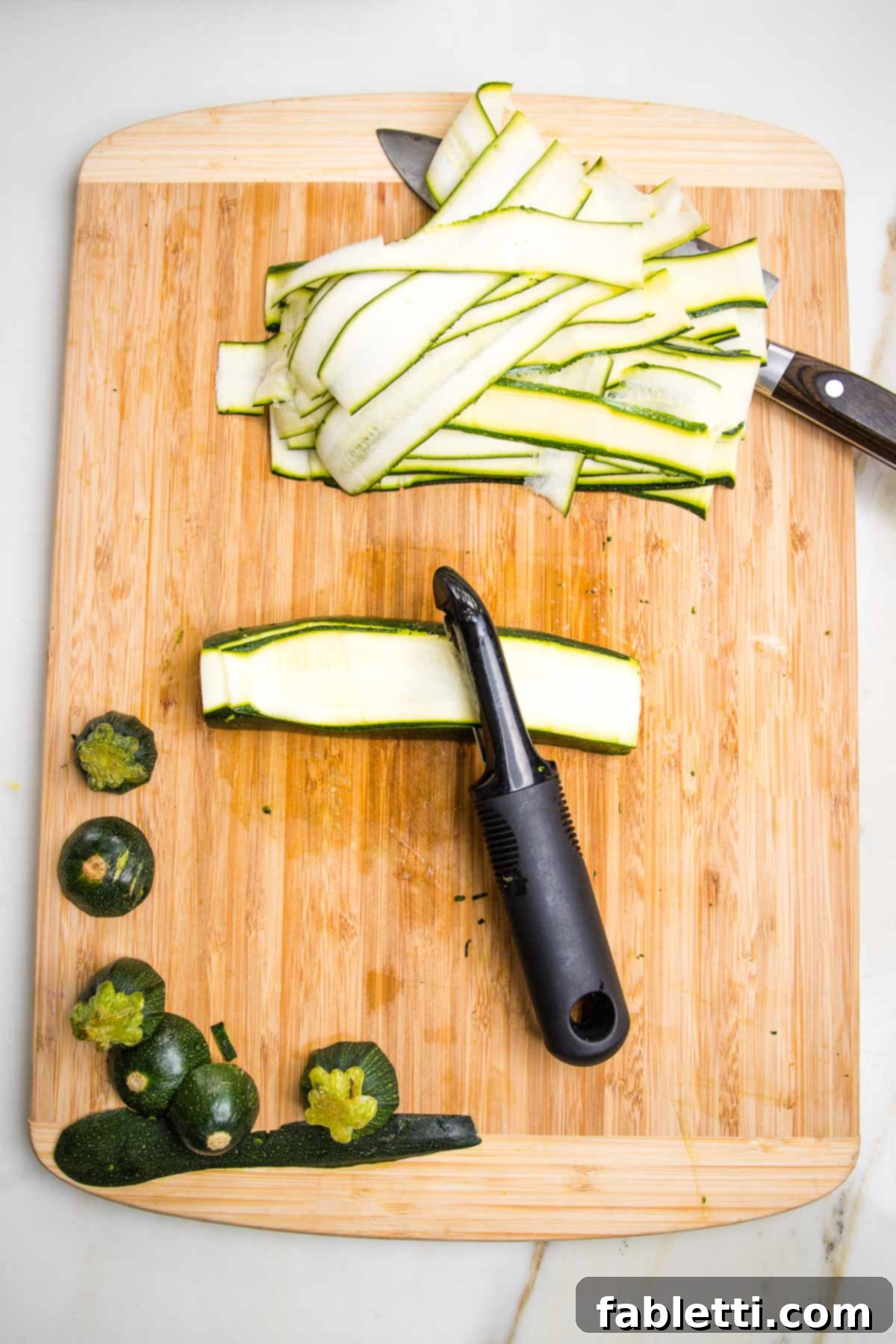 Plant-Based Zucchini Ricotta Rolls 6 Preparing long strips of zucchini for lasagna roll ups. A vegetable peeler makes long thin strips when pulled across the length of a zucchini after it's been trimmed.