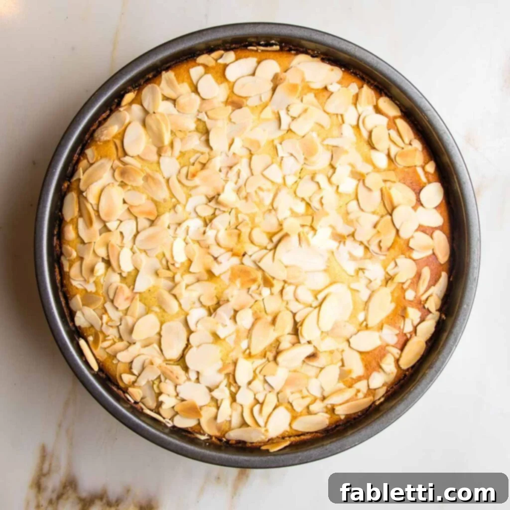 Cake batter with sliced almonds on top, ready for oven.