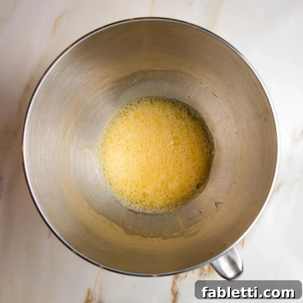 Mixed wet ingredients for lemon cake, yellow and bubbly.