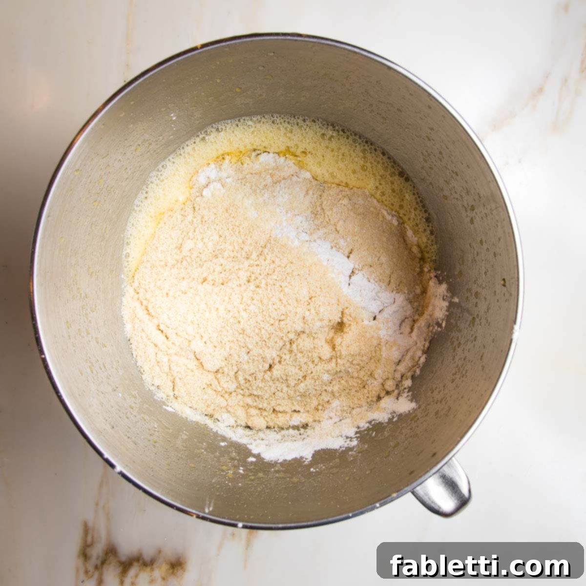 Adding dry ingredients to wet ingredients for lemon cake.