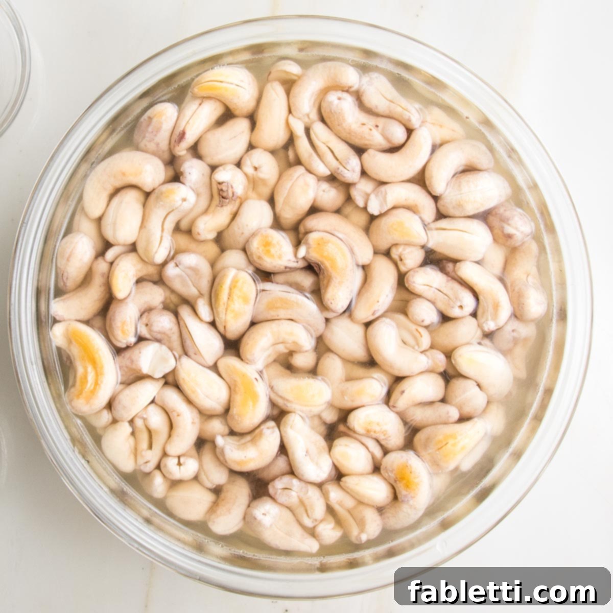 Glass bowl filled with cashews, covered in water. Doubled in size from soaking.